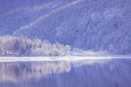 古时冬季风景反射湖雪树和山丘图片