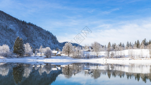 古老的冬季风景反思湖房屋雪树和山岳图片