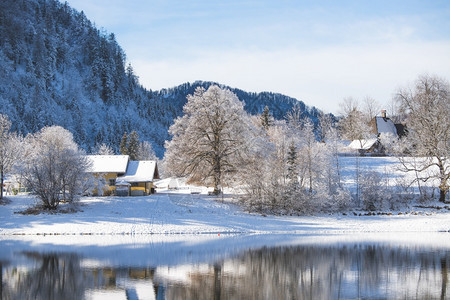 古老的冬季风景反思湖房屋雪树和山岳图片
