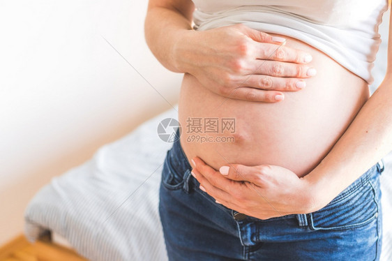 孕妇穿着蓝色牛仔裤摸肚子图片