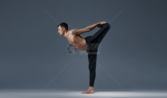 雄瑜伽使巴朗氏菌处于一种困难的姿势灰色背景强健的男子在做瑜伽运动麻风病训练高度集中健康的生活方式雄瑜伽使巴朗氏菌处于一种困难的姿图片