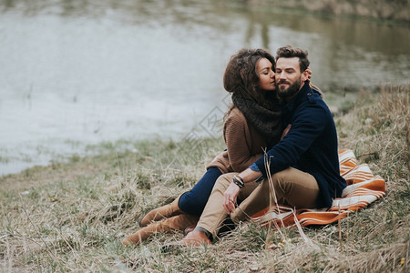 快乐的情侣坐在湖岸边拥抱图片