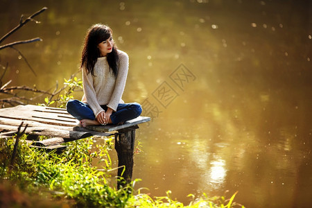 坐在老桥上赤脚的年轻女子夏天绿林湖边和晚上的空气带来放松冥想享受自然和梦想的氛围坐在老桥上赤脚的年轻女子夏天享受自然和梦想的氛围图片