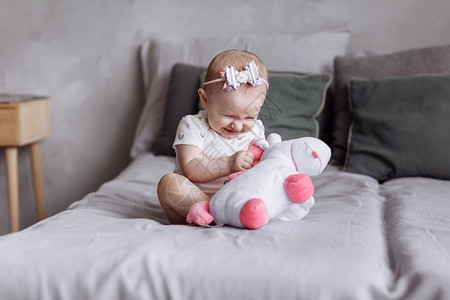 可爱的小女孩在家里床上玩具独角兽童年的一天概念快乐的婴儿和家庭日可爱的小女孩在家里床上玩具独角兽童年的一天概念快乐的婴儿和家庭日图片
