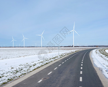 在蓝天下阴地的杜特奇省佛莱沃兰地的阴上风力涡轮机和靠近雪覆盖的田地图片