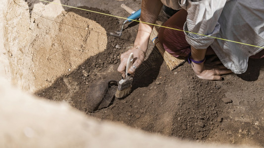 考古学家用手盆挖掘从考古遗址中回收老陶器图片