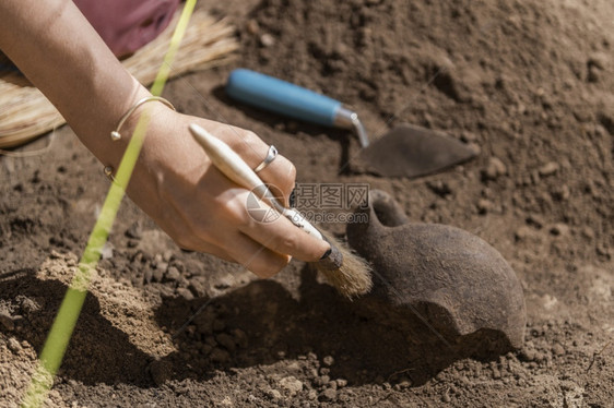 在考古遗址挖掘老陶器文物的女考古学家图片