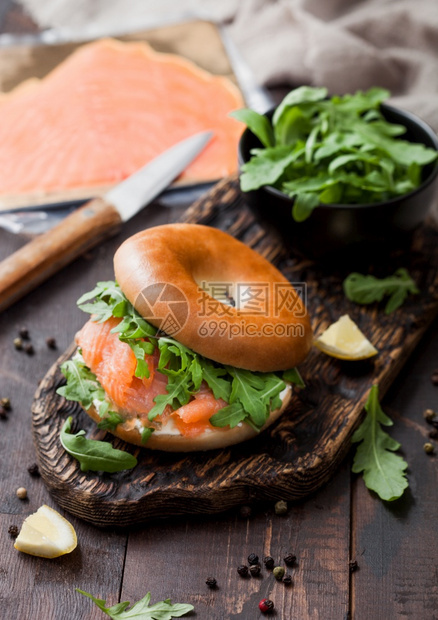 新鲜健康有机三明治配百吉饼和鲑鱼奶油酪和野生火箭装在切肉板上木制背景的熏鲑鱼袋图片