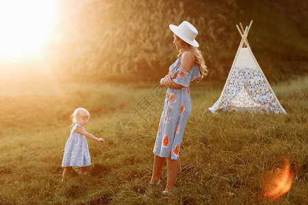 美丽的母亲与女儿一起在田野里玩假发在户外渡花园或公里过着美丽的夕阳光在田里玩得开心在田野里玩得开心在田外度假户共时光在花园或公里图片