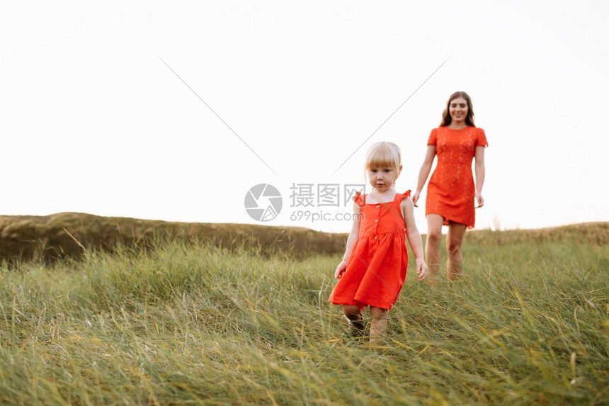 年轻美丽的母亲和小女儿在暑假时大自然中行走母亲和女孩在日落时田里玩耍母亲日友好家庭的概念友好家庭的概念图片
