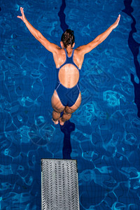 女潜水员从板跳进游泳池图片