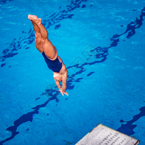 女潜水员从板跳进游泳池图片