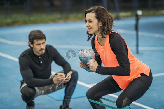 与个人健身教练合作与女客户Kettlebell锻炼户外妇女进行个人教练图片