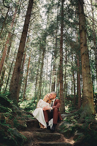 新婚娘在夏日的绿林中快乐新婚娘穿着长白色礼服新郎穿着红色西装正在拥抱新婚日快乐夫妇在夏日的绿林中快乐新婚娘穿着长白色礼服正在拥抱图片