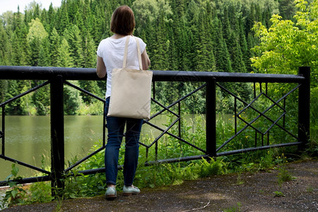妇女携带空的可再用购物袋靠近桥梁护栏模型女手拿着帆布生态友好型袋模拟图片