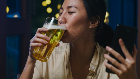 亚洲年轻女士喝酒啤享受欢乐的瞬间晚宴新年节活动通过视频电话在线庆祝晚上家打电话社交不和隔离预防冠状图片