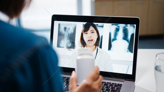使用电脑笔记本的亚洲年轻女士在视频电话中谈论一种疾病在家中客厅与资深医生进行在线咨询图片