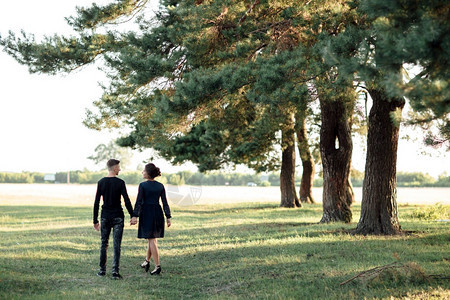 穿黑衣服的男女在户外约会浪漫关系情人节在夏日公园散步的年轻情侣手牵人节图片
