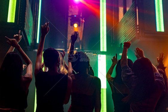 在迪斯科夜俱乐部跳舞的人休光片到DJ在舞台上的音乐新年晚会和夜生活概念在迪斯科夜俱乐部跳舞的人休光片到DJ在舞台上的音乐图片