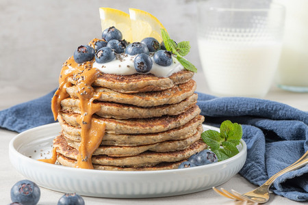 健康的夏季早餐自制的经典美式煎饼鲜蓝浆果柠檬酸奶和花生酱早安灰色石头背景图片