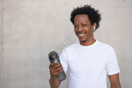 African体育男子在户外放风喝着一瓶水运动和健康的生活方式图片