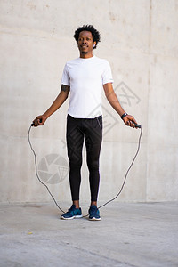 非洲运动员带着耳机在户外跳绳锻炼图片