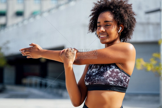 非洲女运动员伸展手臂在户外锻炼前暖身图片