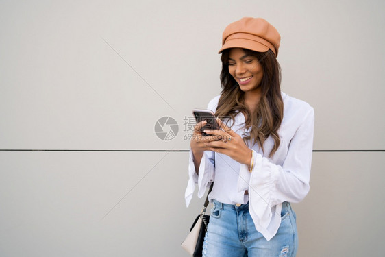 年轻女在露天宿街头时使用手机的肖像城市和通信概念图片
