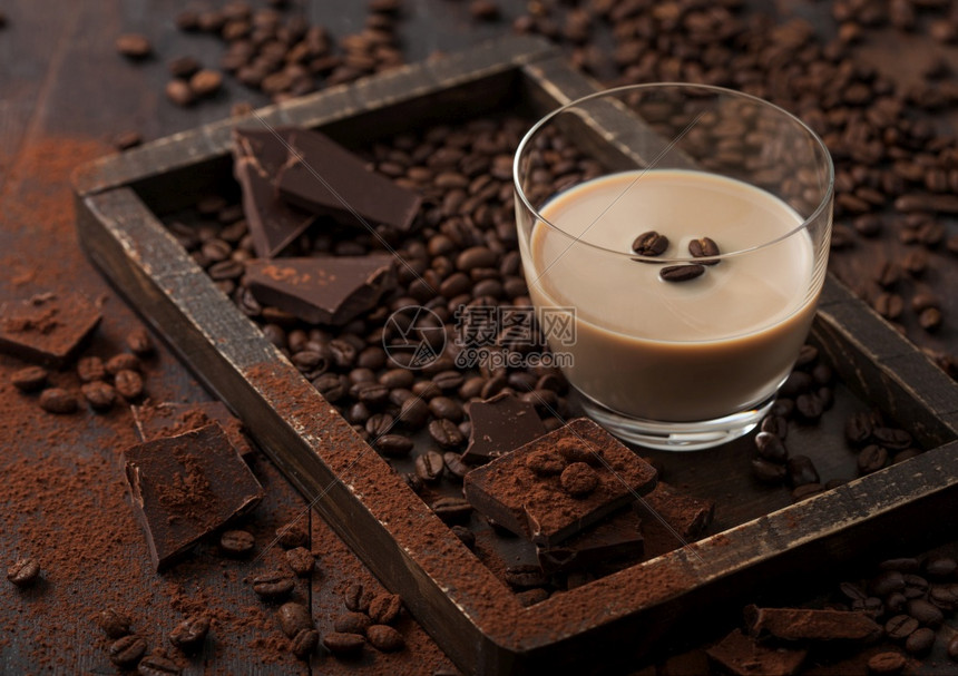 咖啡豆和黑巧克力粉末的玻璃爱尔兰奶油桶深木底质图片
