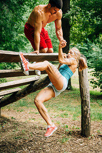 年轻肌肉造夫妻在健身足迹上锻炼男给女人拉手图片