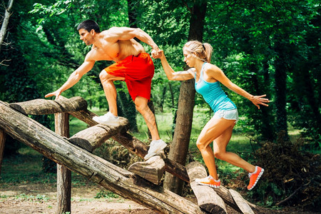 年轻肌肉造夫妻在健身足迹上锻炼男给女人拉手往上爬图片