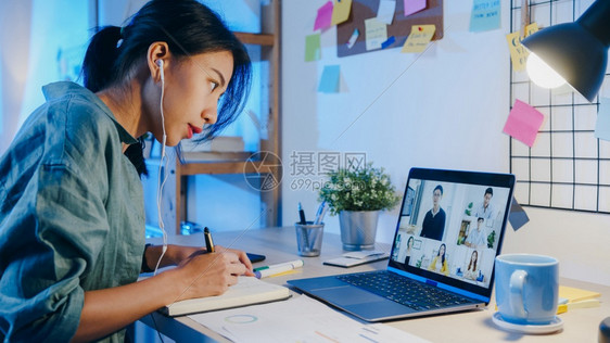 亚洲女商人使用笔记本电脑与同事在客厅的视频电话会议中谈论计划夜间工作超负荷远程工作社交疏远冠状隔离图片
