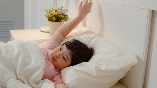亚洲年轻女孩在家醒来亚洲女孩童睡了一夜后放松休息躺在床上早家的卧室里感到舒适和平静图片