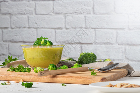 准备吃新鲜热辣的西兰花纯汤在木制桌子上用板块填西兰花和巴尔叶片图片