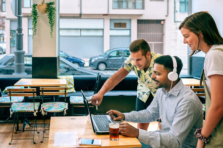 与朋友一起喝咖啡一群朋友与咖啡馆的笔记本电脑一起玩视频话游戏背景