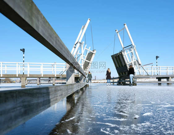 人们在寒冷的水中滑过吊桥在寒冷的冬天图片