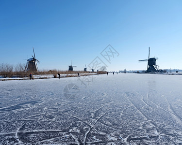 在阳光明媚的冬日人们在寒冷的中与许多风车一起滑雪在寒冷的人群中图片