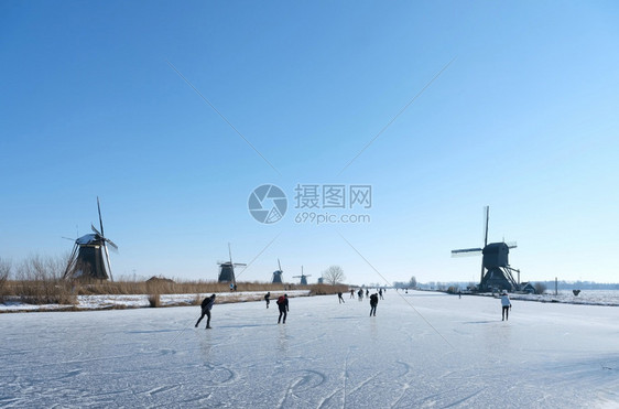 在阳光明媚的冬日人们在寒冷的中与许多风车一起滑雪在寒冷的人群中图片