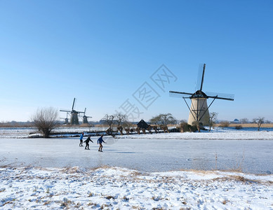 在阳光明媚的冬日人们在寒冷的中与许多风车一起滑雪在寒冷的人群中图片