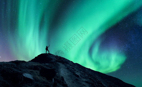 北极光和站在挪威山上举起双臂的站着人月光和圆背影Aurorahotalis和幸福的人天空与星和绿极光夜间风景与极光图片