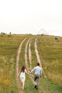 年轻美貌夫妇在夏季亲手田里散步长发女人和理男夏天年轻美貌夫妇亲手在田里散步图片