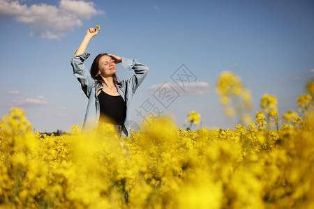 在黄开花的种子田中年轻女性。 在黄开的种子田中年轻女性。图片