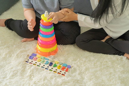 亚洲母亲教她女儿使用多彩的堆叠环塔教育研究玩具实用技能的家庭学习时间在科罗纳大流行的隔离中在家里学习庭时间图片