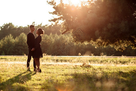 穿黑衣服的男女在日落时有户外约会浪漫关系情人节侣在夏季公园散步情人节图片