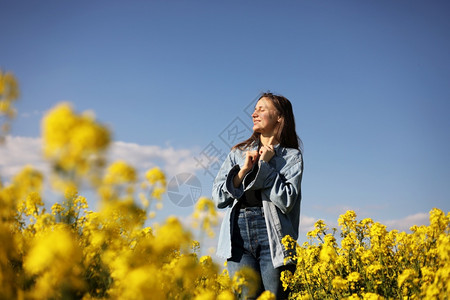 在黄开花的种子田中年轻女性。 在黄开的种子田中年轻女性。图片