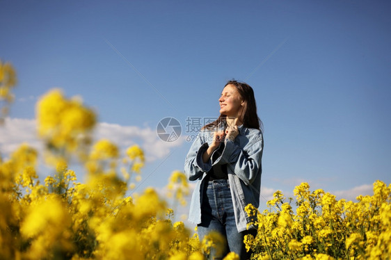 在黄开花的种子田中年轻女性。 在黄开的种子田中年轻女性。图片