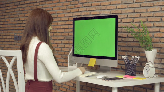 亚洲女商人在家工作的年轻人在网络摄像头视频电话会议上用计算机和空白绿屏间在桌上工作冠状概念的隔离中工作图片