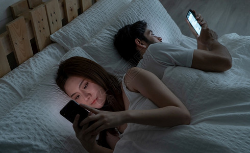 一对不相爱的情侣深夜在家卧室用智能手机睡觉感情问题焦虑离婚家庭图片