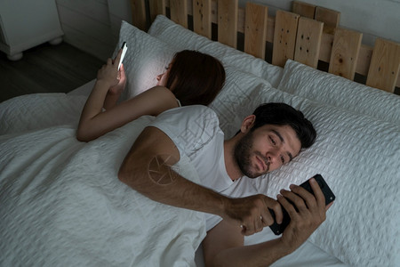 一对不相爱的情侣深夜在家卧室用智能手机睡觉感情问题焦虑离婚家庭图片