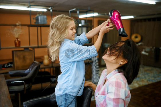 母亲和女儿在化妆沙龙使用吹风机妈和小女孩一起玩发型师快乐的童年迷人家庭母亲和女儿在沙龙使用吹风机图片